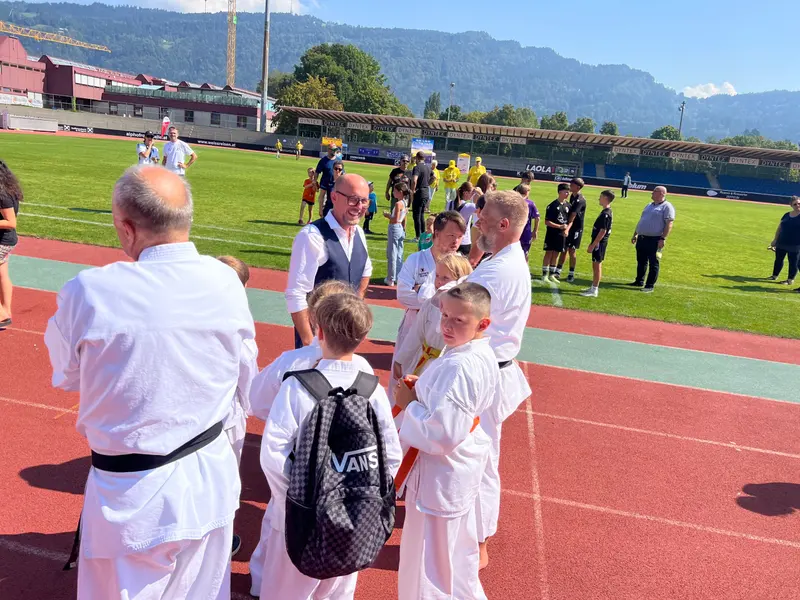 Erwachsene und Kinder in Karategi versammeln sich am Spielfeldrand