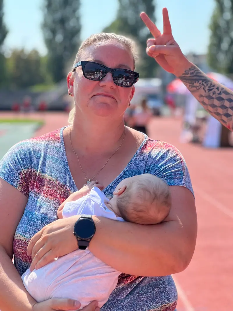 Person mit Sonnenbrille hält schlafendes Baby im Arm