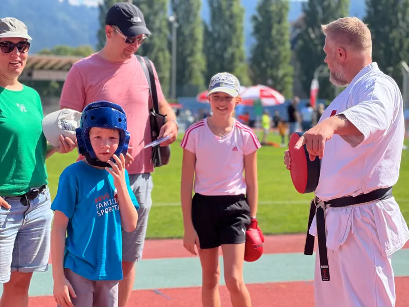 Erwachsener spricht mit Kindern und Eltern auf der Laufbahn