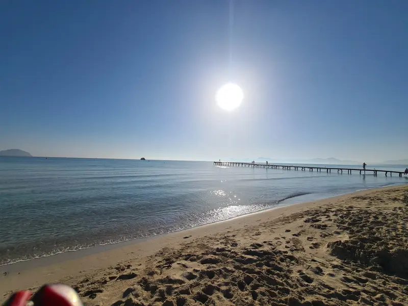 Sonnenspiegelung auf dem Meer, im Hintergrund ein Steg