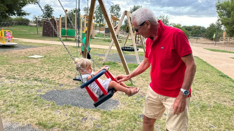 Erwachsener schiebt ein Kind auf einer Schaukel im Park