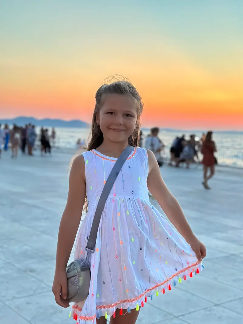 Kind lächelt auf einer Promenade bei Sonnenuntergang