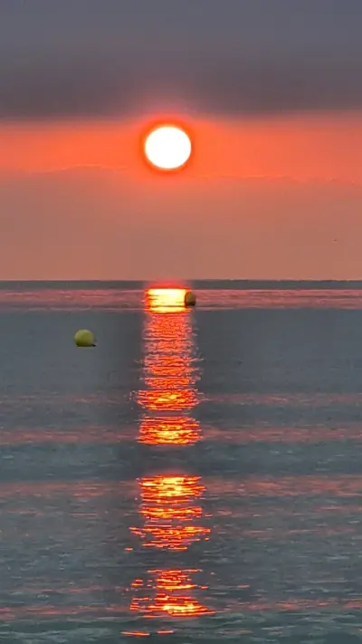 Sonne geht über dem Meer unter, spiegelt sich im Wasser