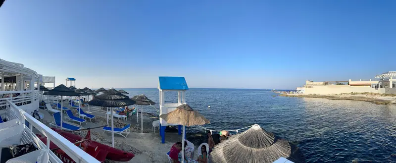 Blick entlang eines Strandes mit Sonnenschirmen und Meer