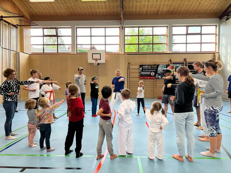 Gruppe übt gemeinsam Kicktechniken in der Turnhalle