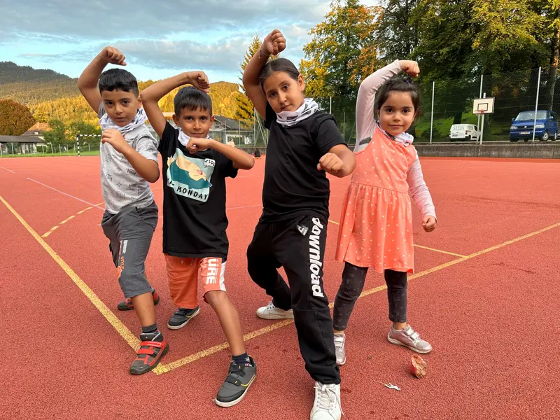 Gruppe Kinder posiert mit erhobenen Armen im Freien