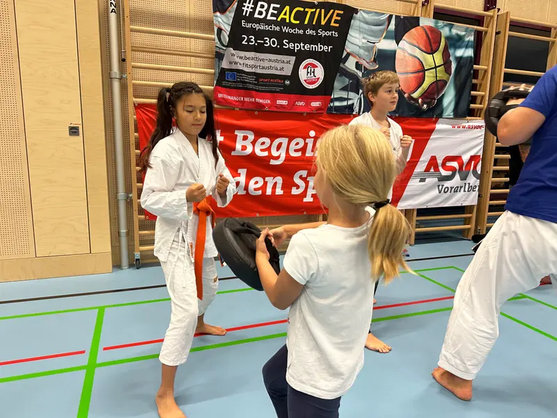 Zwei Kinder im Karategi üben Techniken mit Schlagpolster