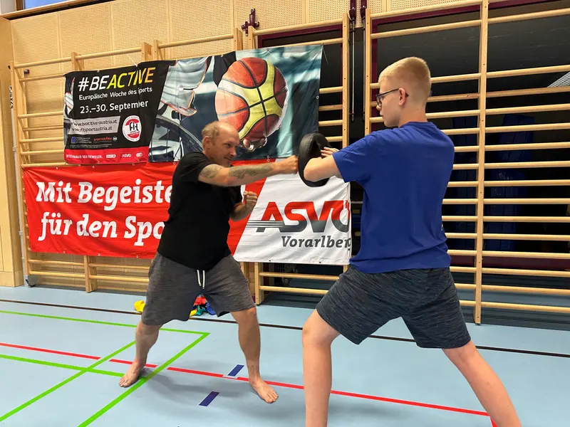 Trainer und Kind üben gemeinsam eine Schlagtechnik