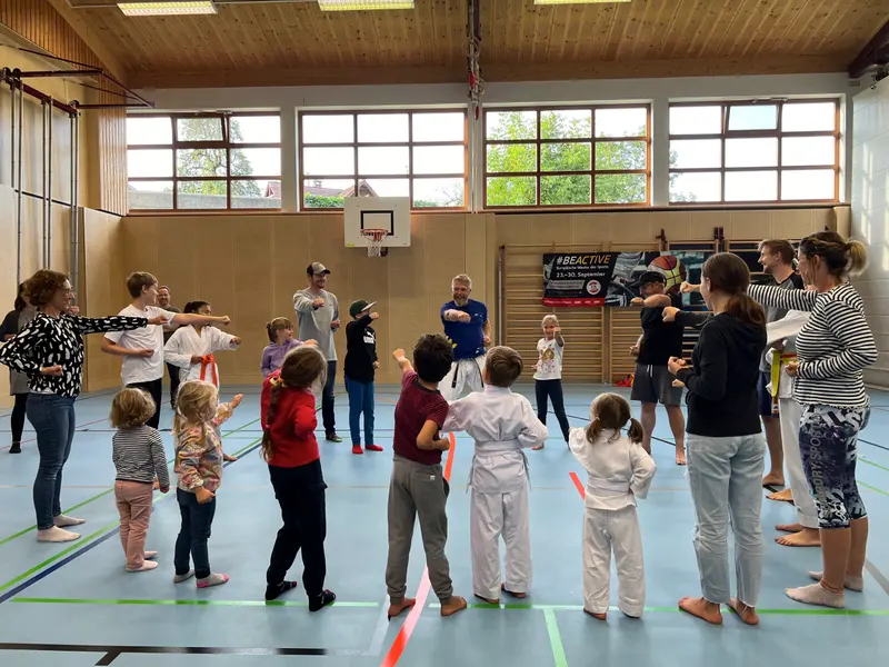 Kreis aus Kindern und Erwachsenen streckt Arme zur Mitte