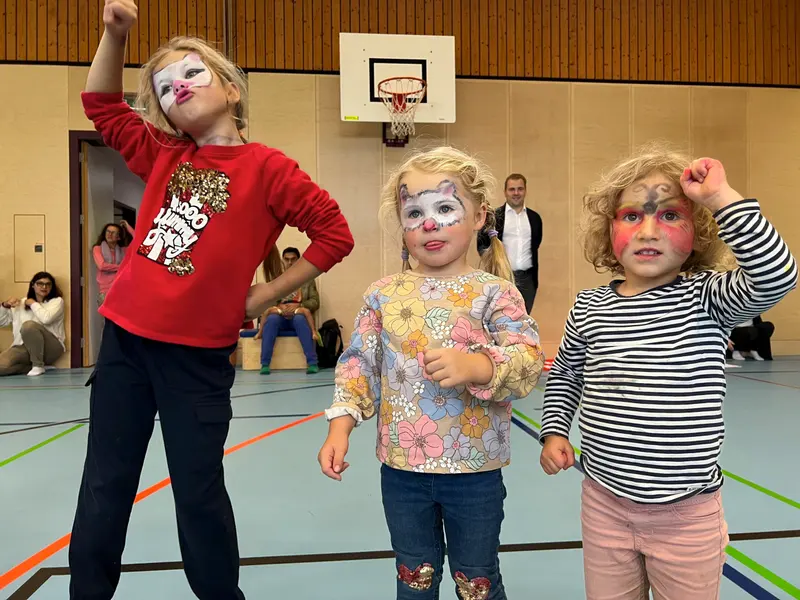 Kinder mit geschminkten Gesichtern posieren mit erhobenen Armen