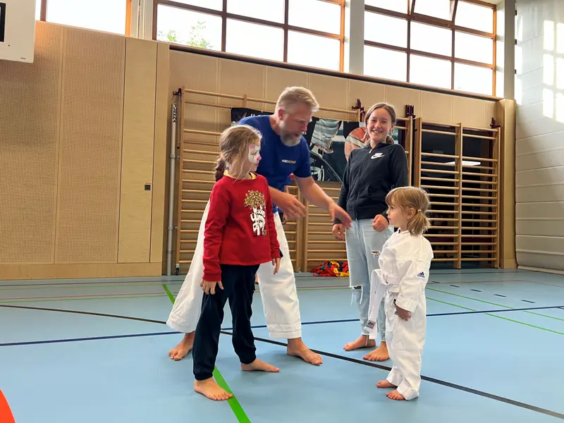 Kinder im Karategi üben Techniken, Erwachsene beobachten