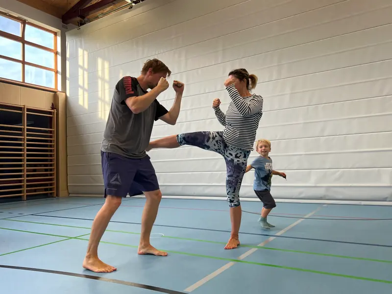 Mann übt Fußtritt, Kind beobachtet in der Turnhalle