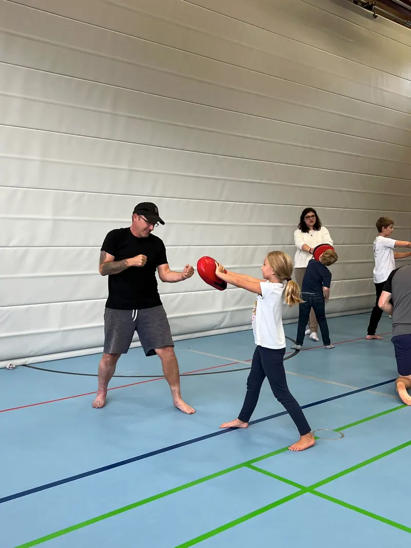 Mann hält Pratze, Kind übt Schlagtechnik in der Halle