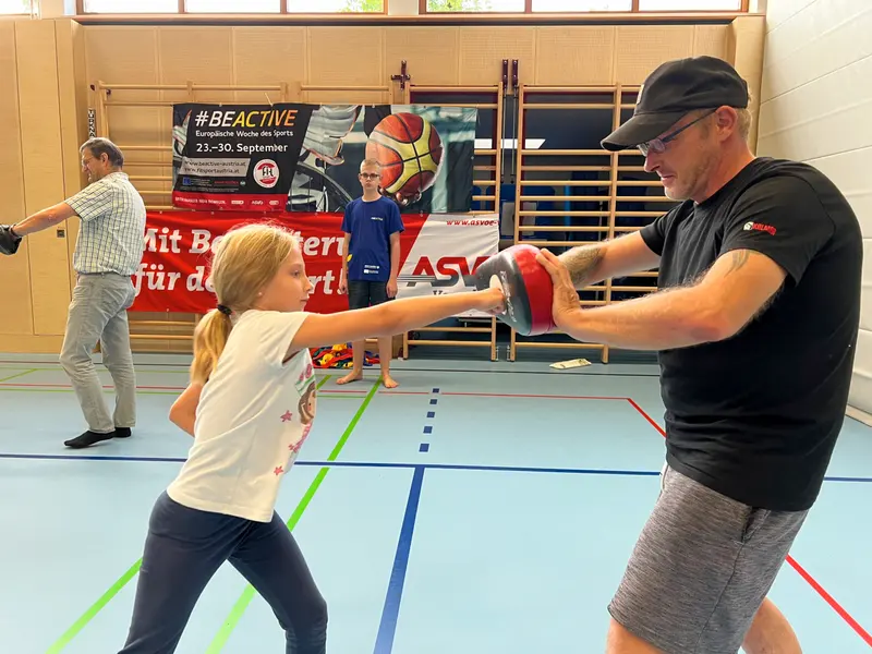Kind schlägt gegen Pratze, die ein Mann hält