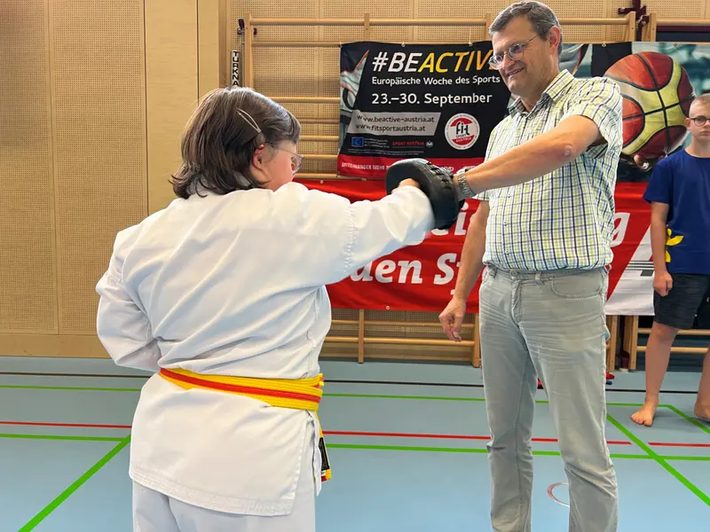 Person im Karategi übt Schlagtechnik gegen Pratze