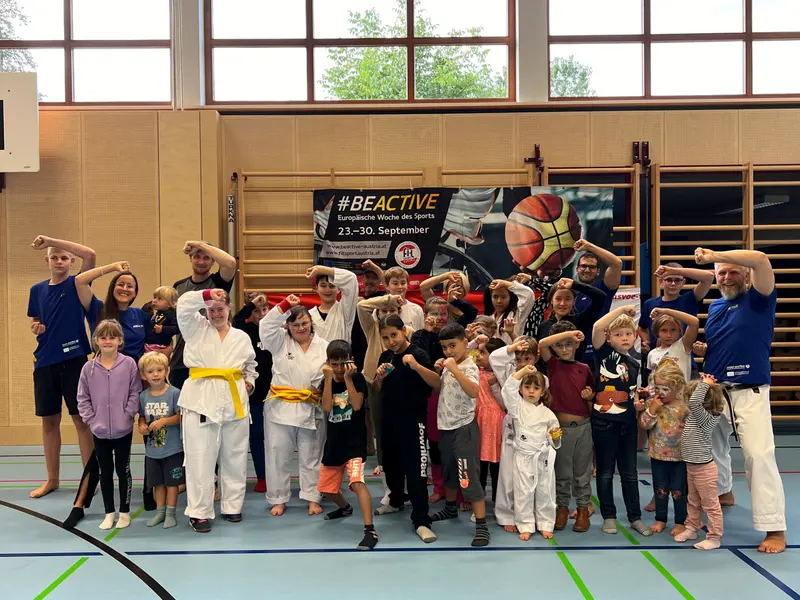 Große Gruppe in Karategi und Freizeitkleidung posiert für Foto