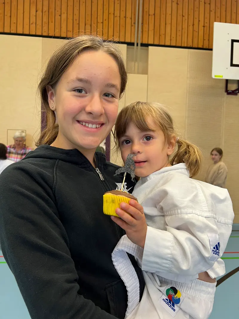 Zwei Kinder posieren lächelnd mit Cupcake in der Hand