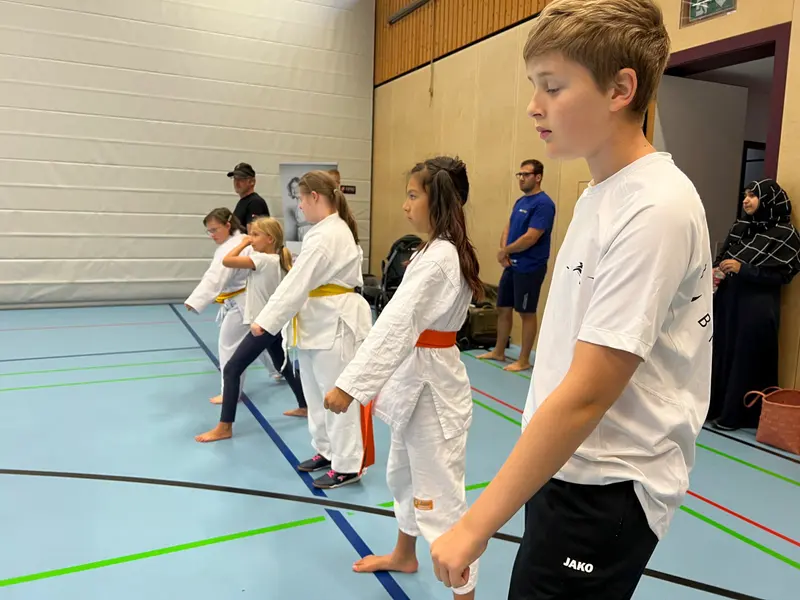Kinder im Karategi laufen hintereinander durch die Halle