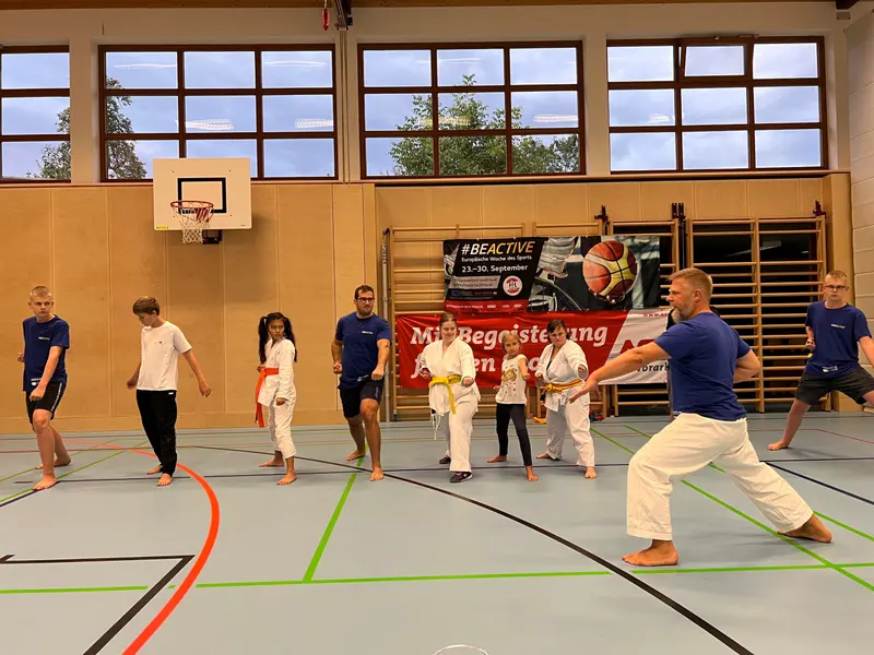 Trainer zeigt Technik vor Gruppe in der Turnhalle
