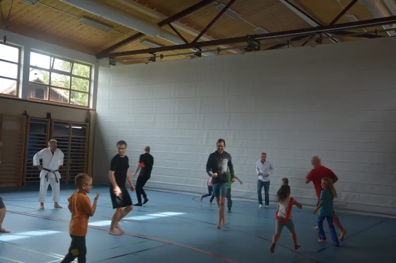 Gruppe aus Kindern und Erwachsenen läuft durch die Sporthalle