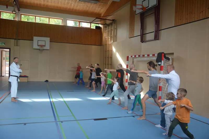 Gruppe aus Erwachsenen und Kindern spielt in der Sporthalle