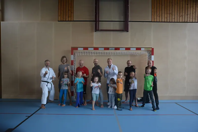 Gruppe aus Erwachsenen und Kindern posiert in der Sporthalle