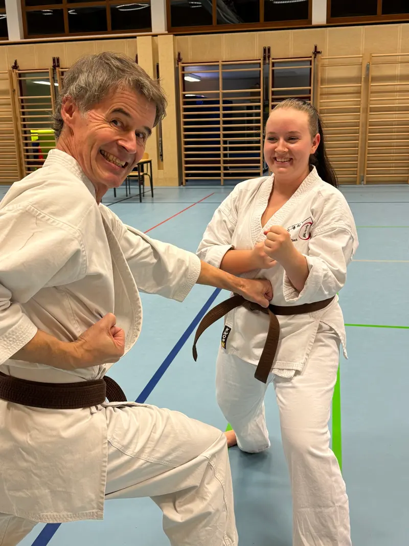 Trainer und Person im Karategi begrüßen sich lachend