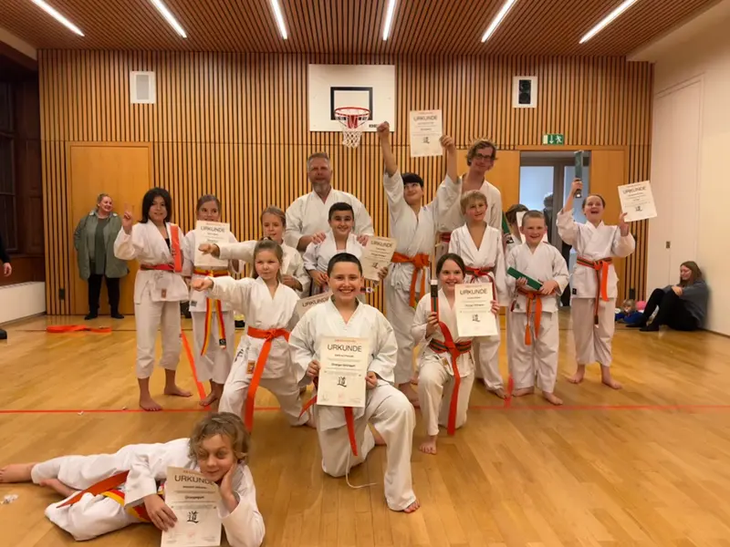 Gruppe von Kindern im Karategi kniet für Gruppenfoto
