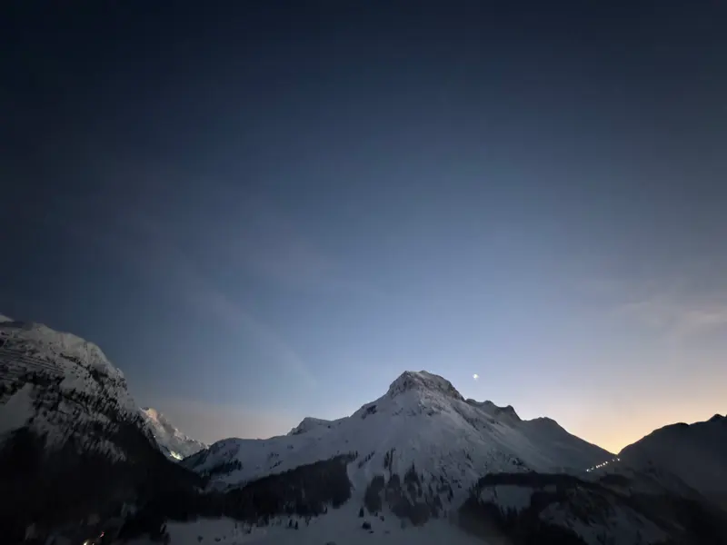Sternenhimmel über schneebedeckter Berglandschaft in der Dämmerung