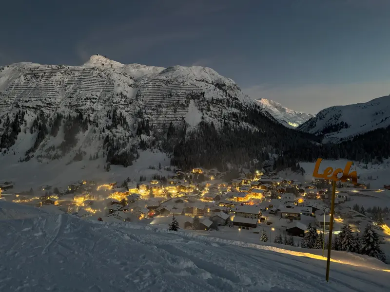 Beleuchtetes Bergdorf in der Abenddämmerung von oben
