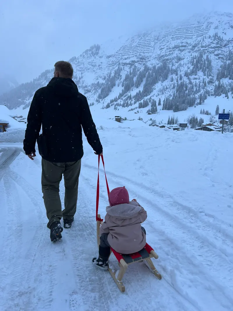 Erwachsene und Kind gehen über verschneiten Weg, Blick von hinten