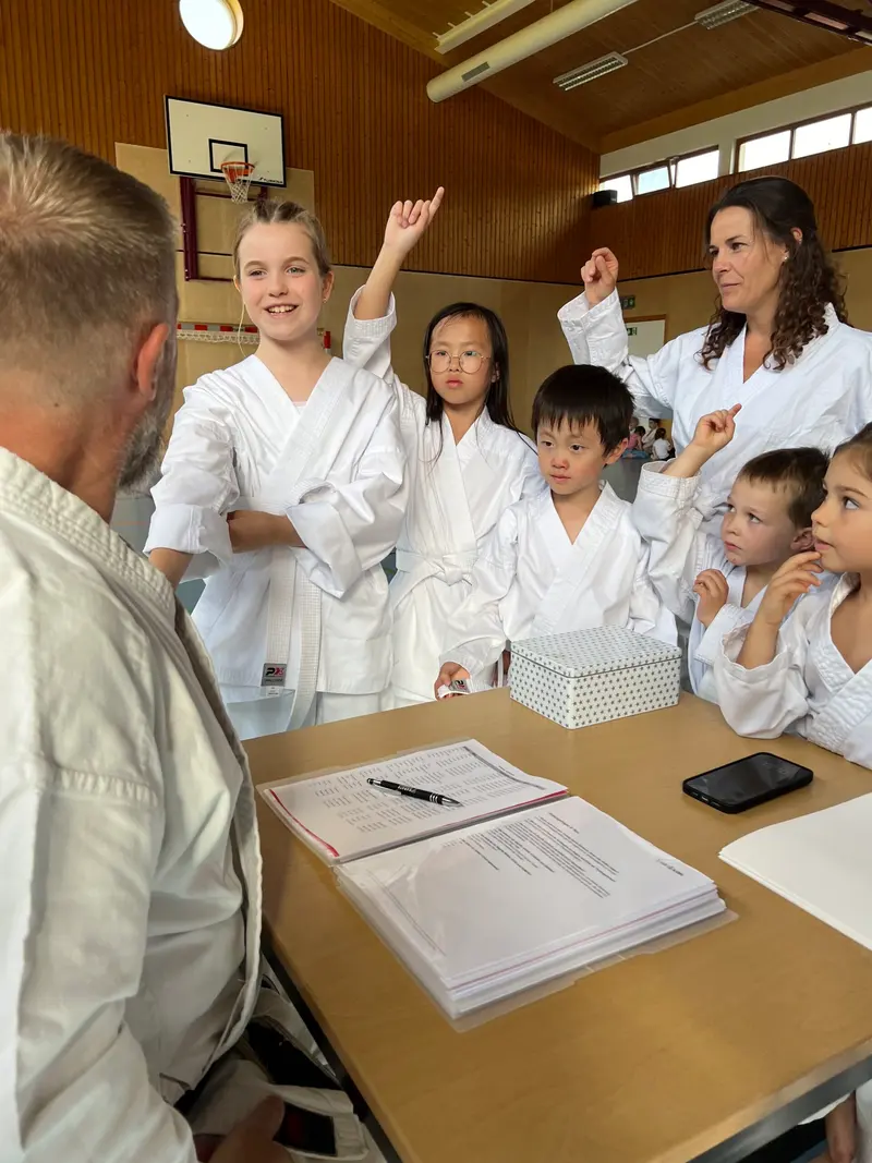Gruppe von Kindern im Karategi steht um Tisch