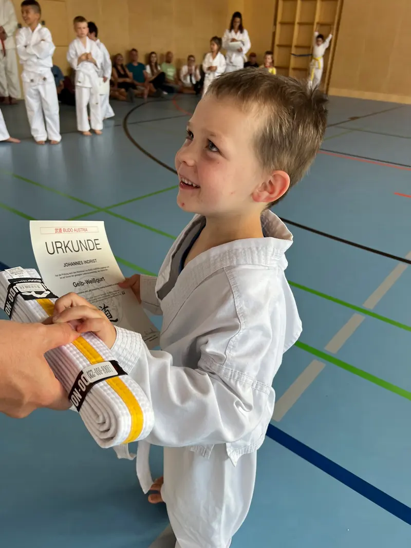 Trainer überreicht Kind einen gelben Gürtel