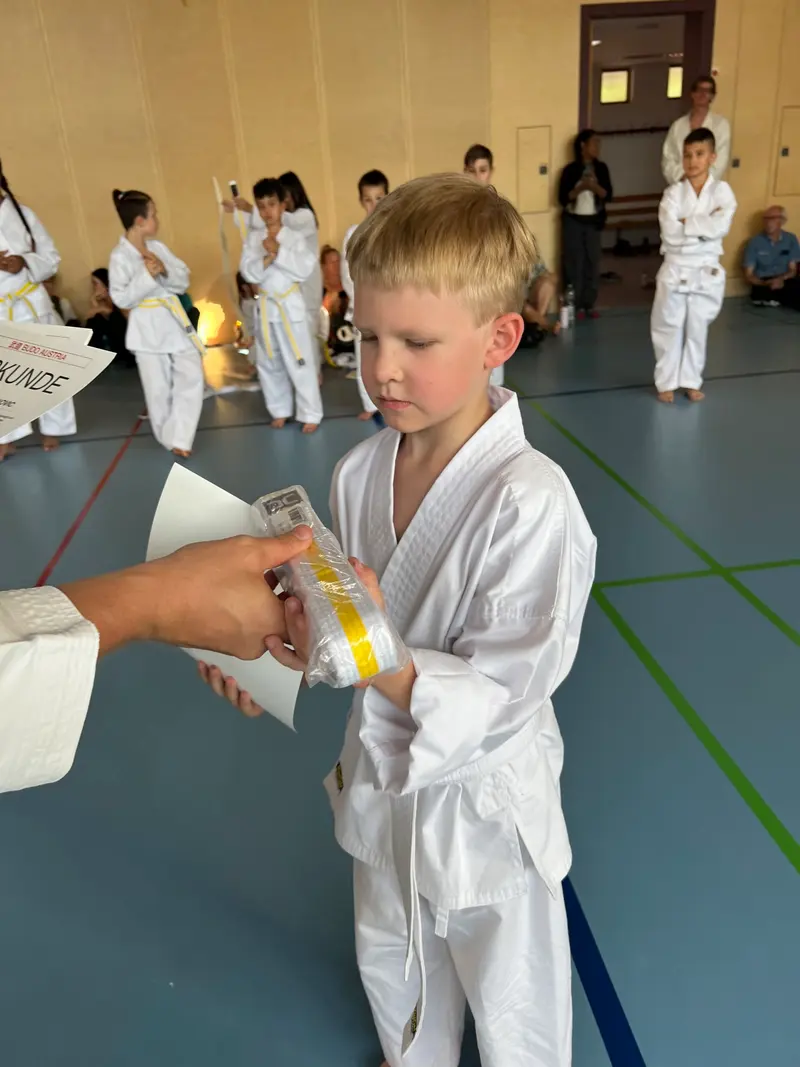 Trainer bindet Kind einen gelben Gürtel um