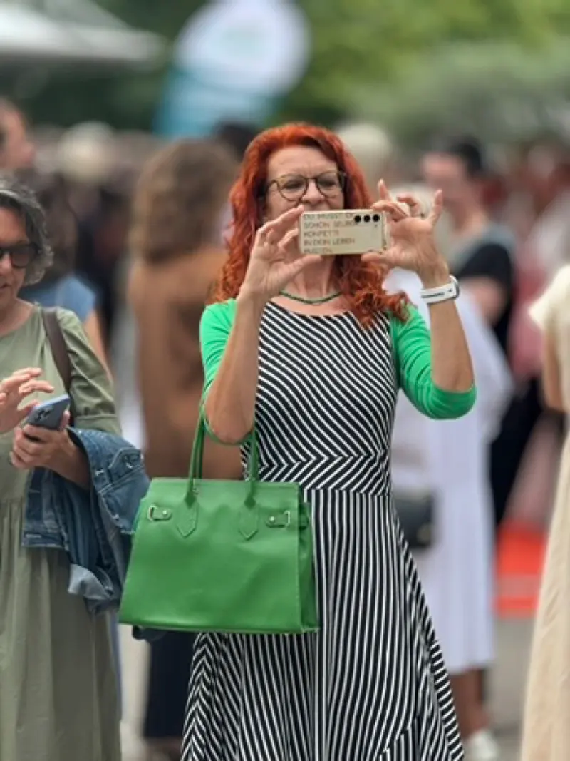 Person fotografiert mit dem Smartphone bei einer Veranstaltung im Freien