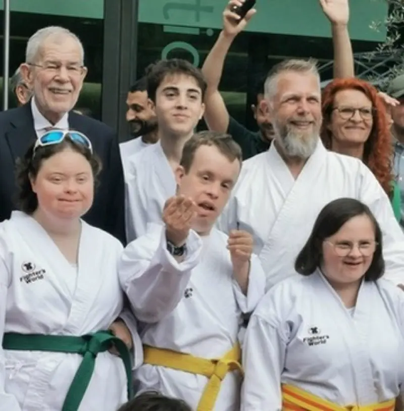 Gruppe in Karategis und Anzügen posiert lächelnd für ein Foto