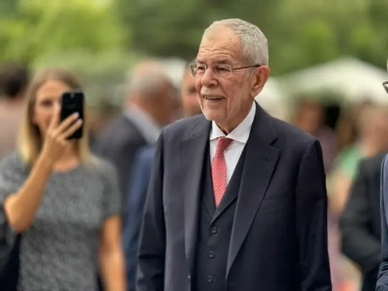 Person hält Smartphone hoch, im Hintergrund eine Person im Anzug