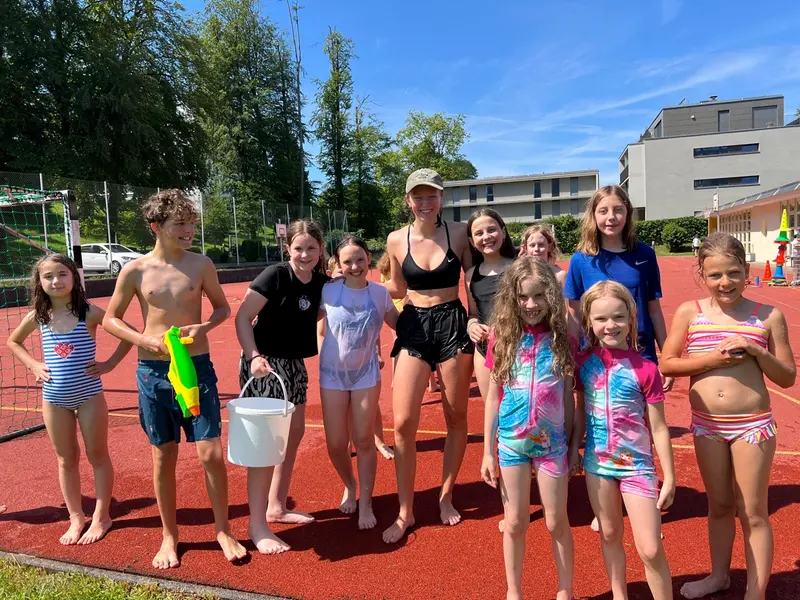 Gruppe Kinder und Jugendliche steht mit Wasserspielzeug auf einem Sportplatz
