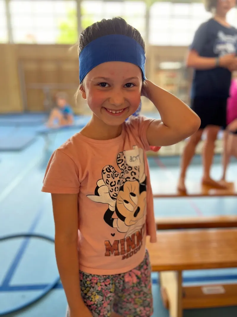 Kind lächelt am Beckenrand eines Schwimmbads