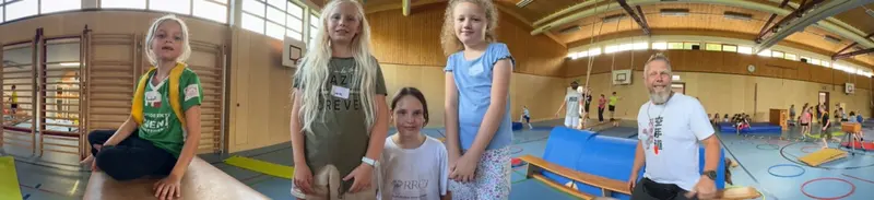 Zwei Kinder stehen lächelnd zusammen im Turnsaal