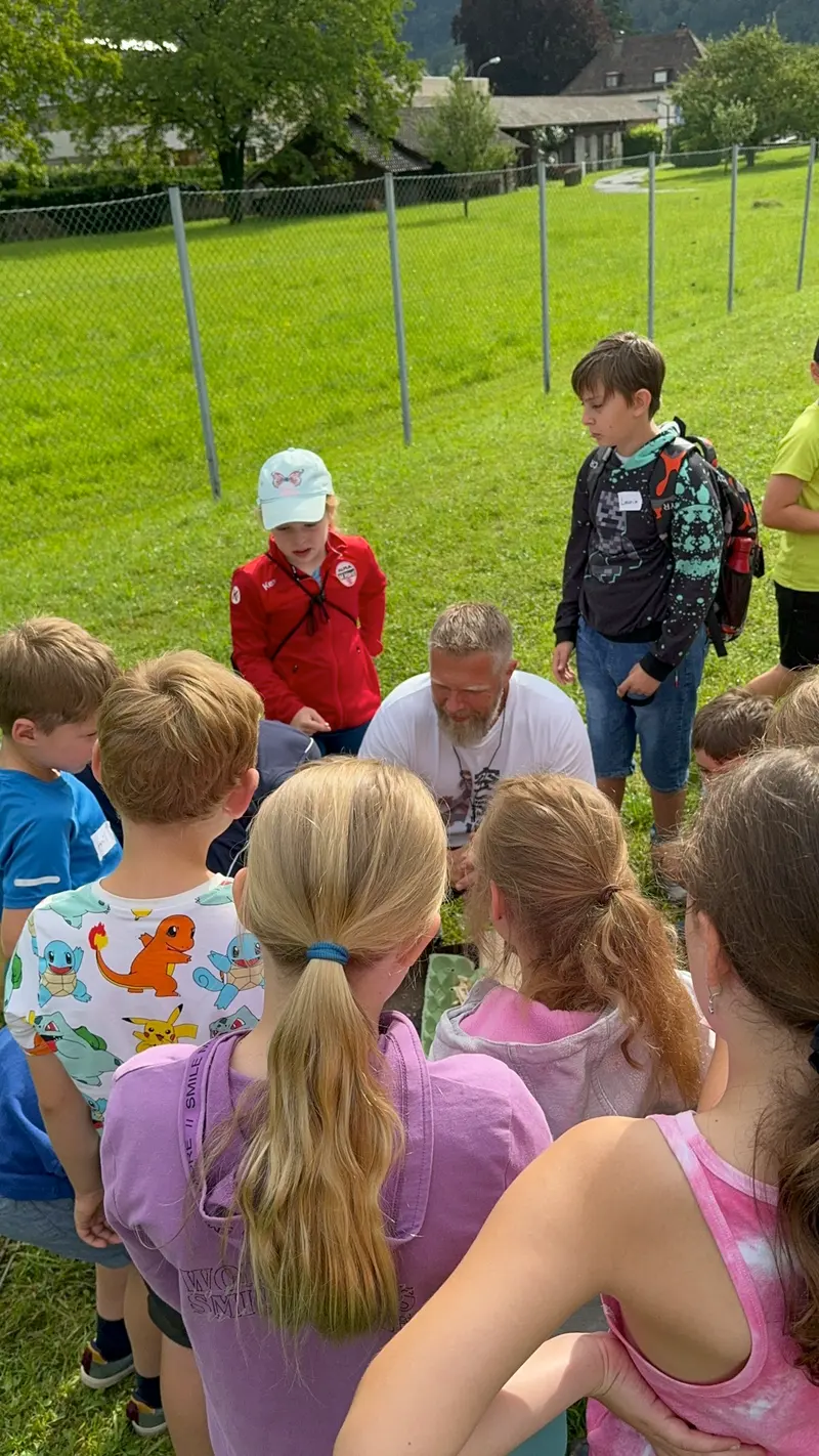 Gruppe aus Kindern und Erwachsenen steht im Kreis im Freien