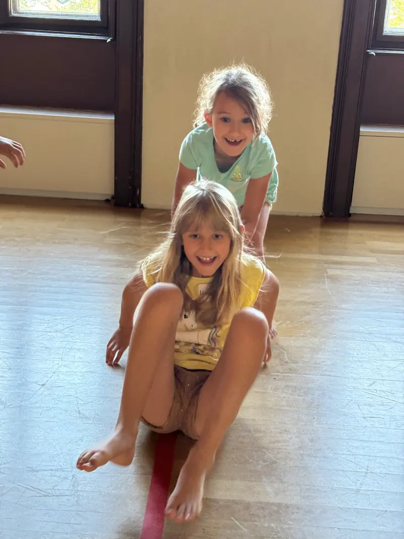 Zwei Kinder spielen zusammen auf dem Boden der Turnhalle