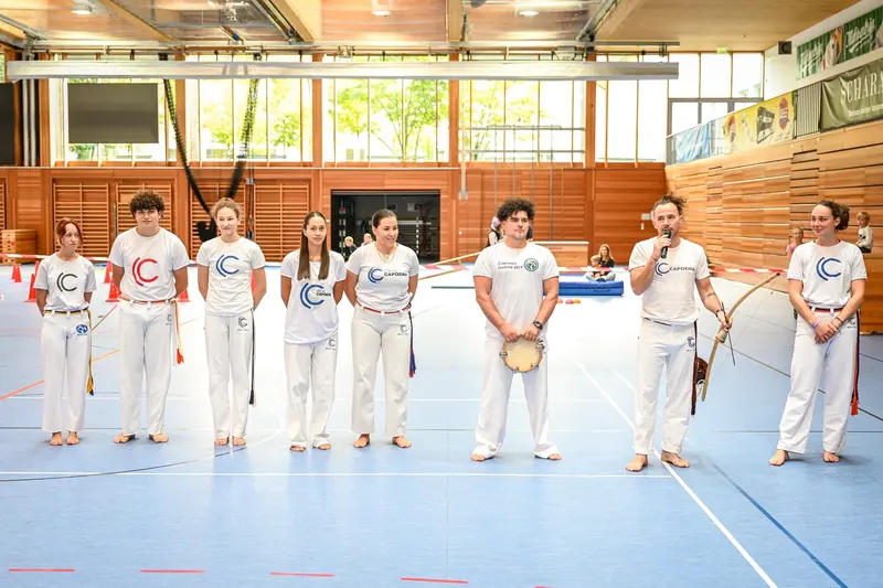 Capoeira-Gruppe in weißer Kleidung mit Berimbau und Trommel