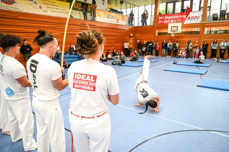 Person schlägt Rad bei Capoeira-Vorführung in der Halle