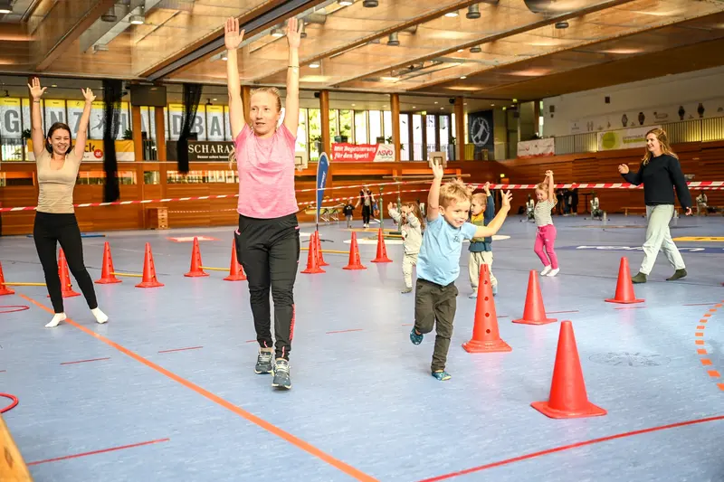 Kinder laufen jubelnd durch einen Hütchenparcours