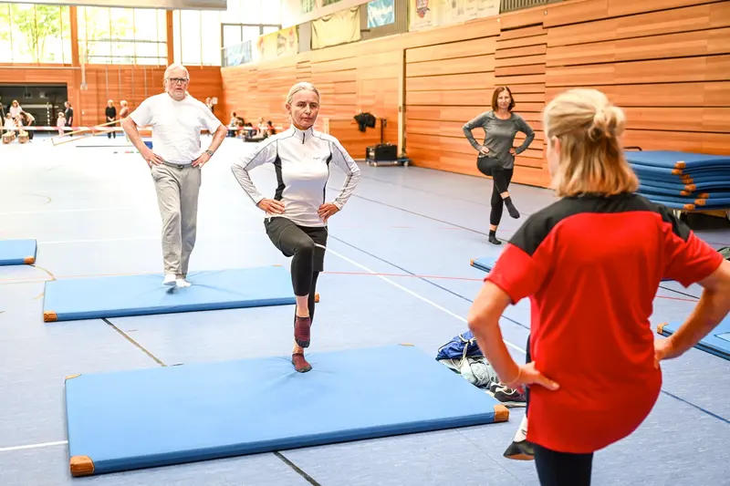 Gruppe balanciert auf einem Bein, Trainerin beobachtet