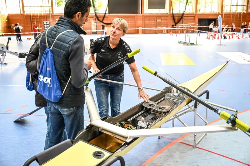 Zwei Personen begutachten ein Ruderboot in der Halle