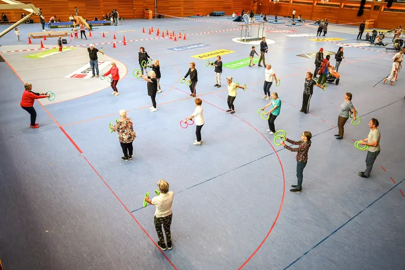 Gruppe steht im Kreis mit bunten Reifen in Halle