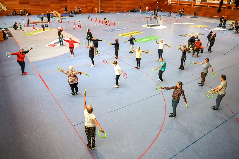 Gruppe hebt Reifen bei Bewegungsübung in der Halle