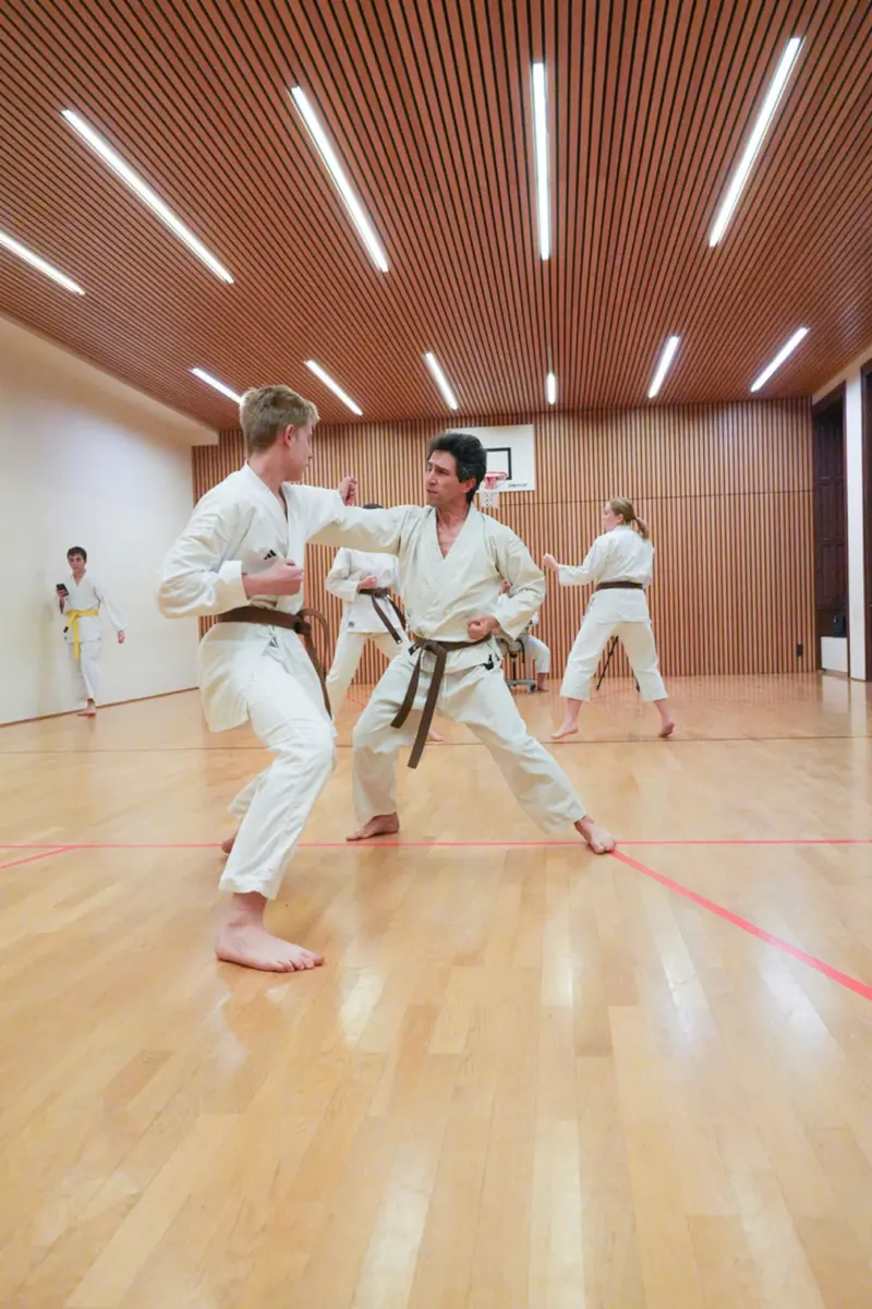 Drei Personen trainieren gemeinsam Kumite in der Sporthalle
